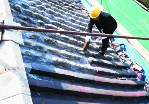 工人对屋顶的琉璃瓦进行拆除，损坏严重的将按照原比例、原有颜色进行定制