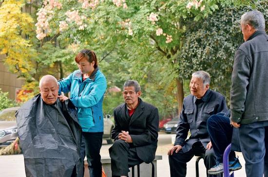 11月9日，在安徽省合肥市蜀山区井岗镇欣塘家园小区广场，47岁的李泽翠在为小区里的老年人免费理发。随着中国人口老龄化的加剧，养老金方面的需求日渐增长。