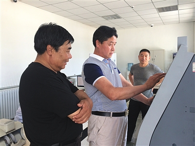 5月11日,在密云区溪翁庄镇东智东村便民服务代办站,60岁的村民梁某(左)请工作人员帮忙给手机充100元话费。 5月11日,在密云区溪翁庄镇东智东村便民服务代办站,60岁的村民梁某(左)请工作人员帮忙给手机充100元话费。