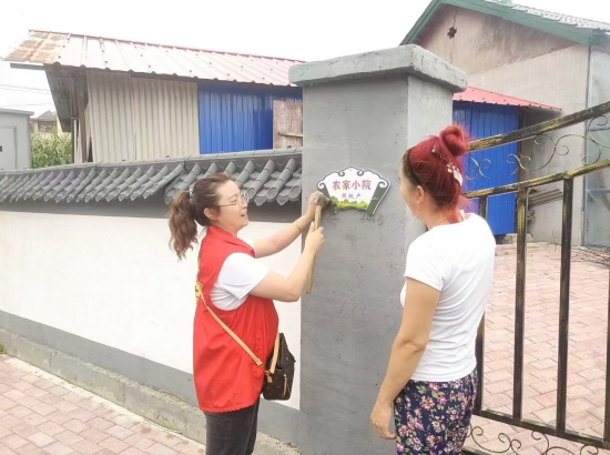 立新村工作人员对干净人家示范户进行挂牌。 王照一 摄.jpeg 立新村工作人员对干净人家示范户进行挂牌。 王照一 摄.jpeg